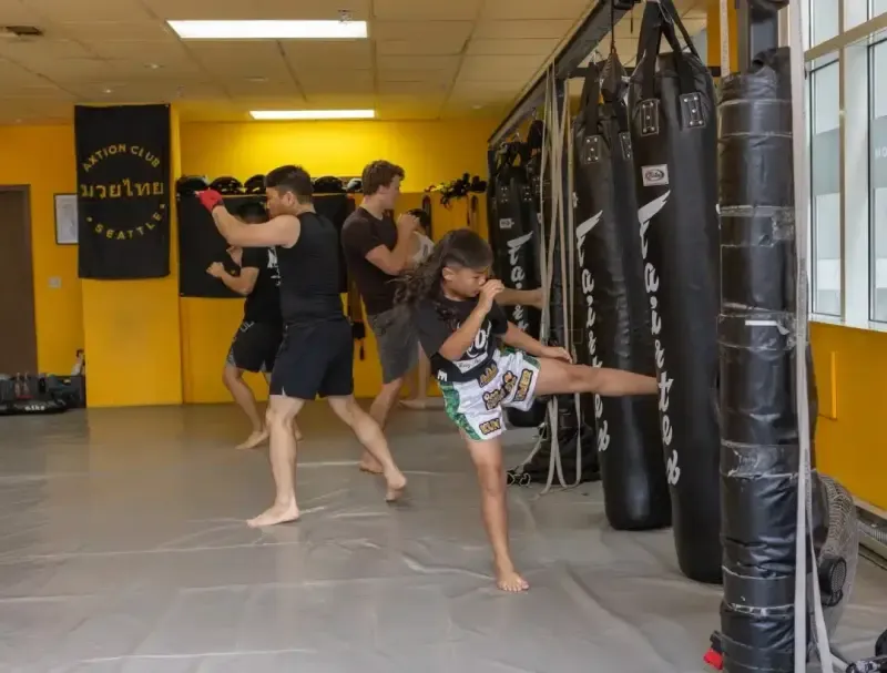 Young member throwing a kick on the heavy bags at Axtion Club
