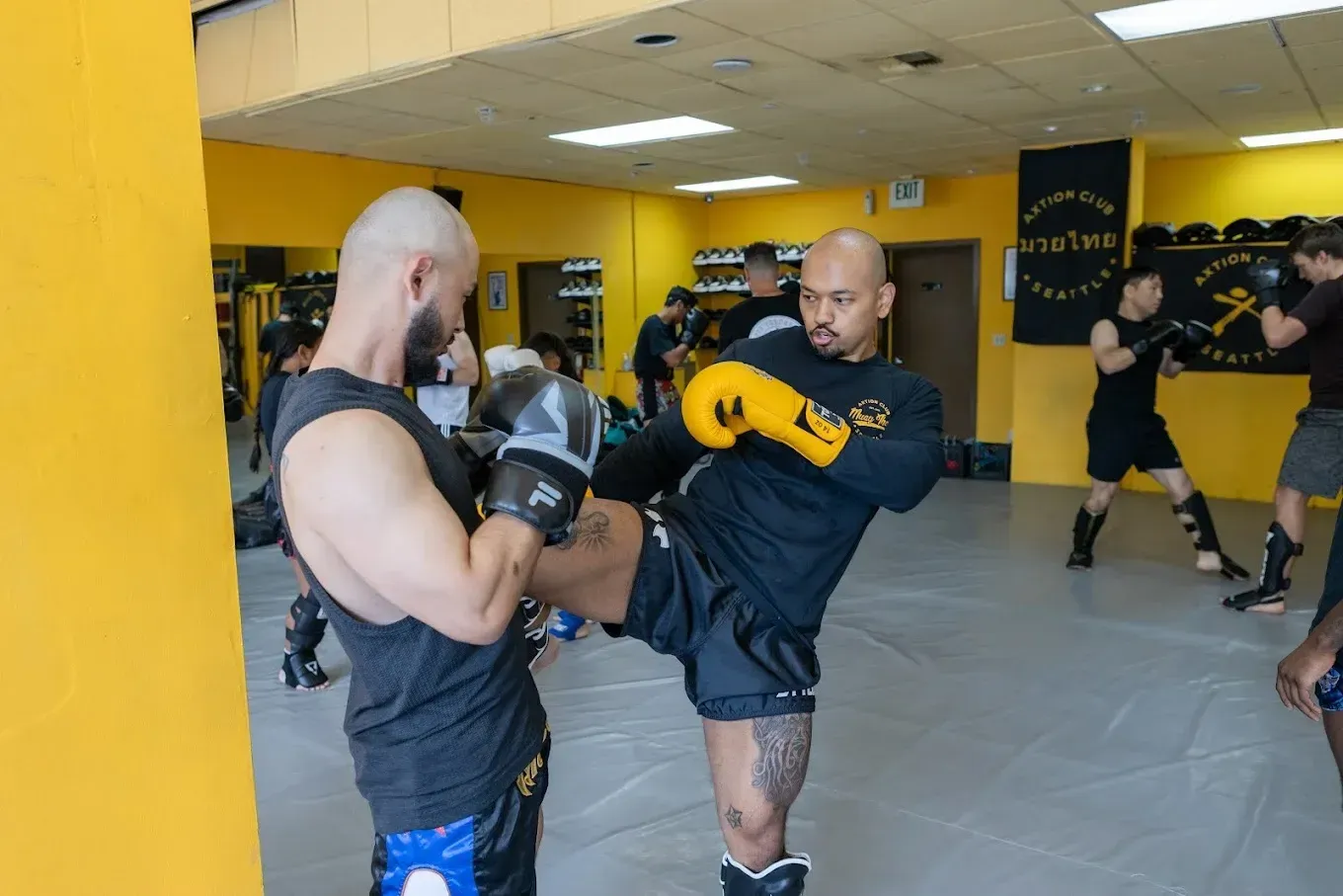 Axtion Club coach holding pads as a member throws a roundhouse kick