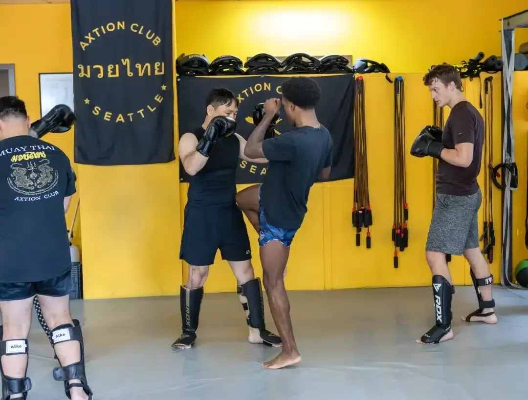 Muay Thai partner drill in front of the Axtion Club Seattle banner
